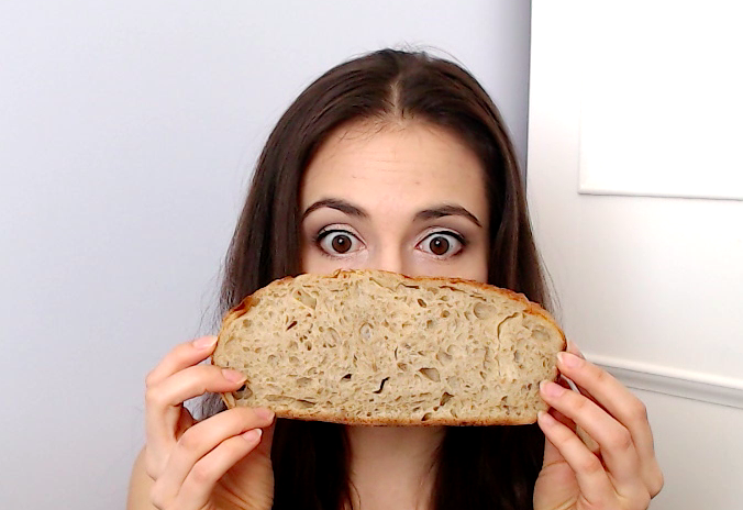girl covering face with slice of bread
