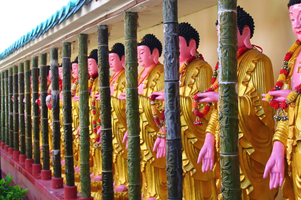 Line of golden robed, buddha sculptures in temple.