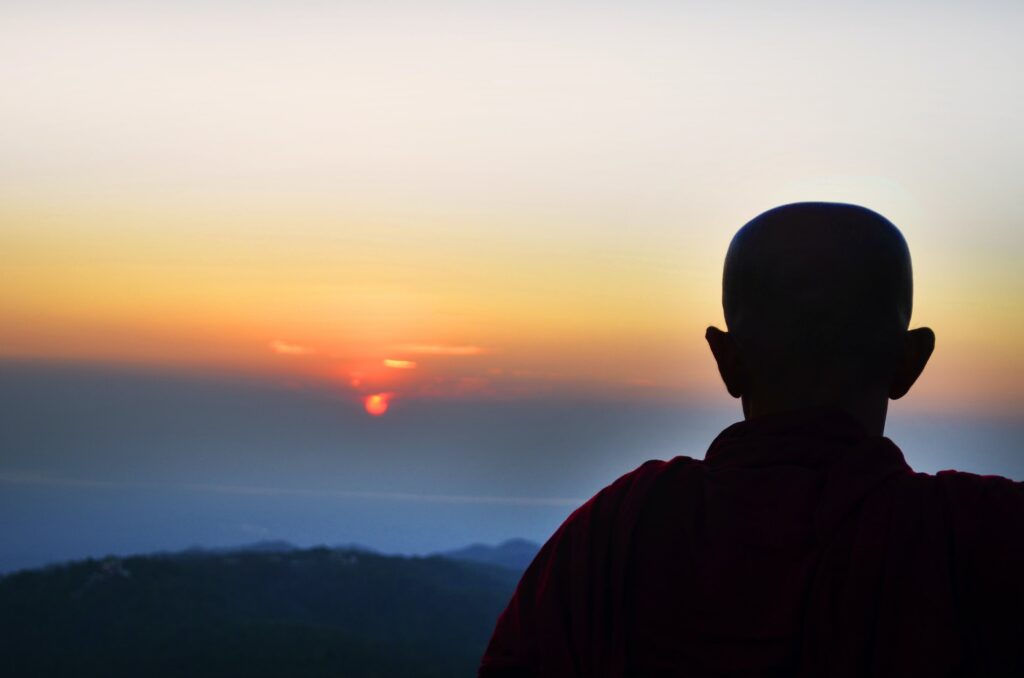 Monk silhouette watching sunrise.