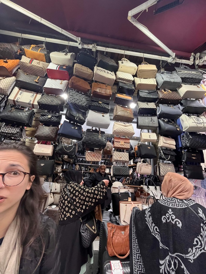Dee in front of hanging purses in market in Istanbul